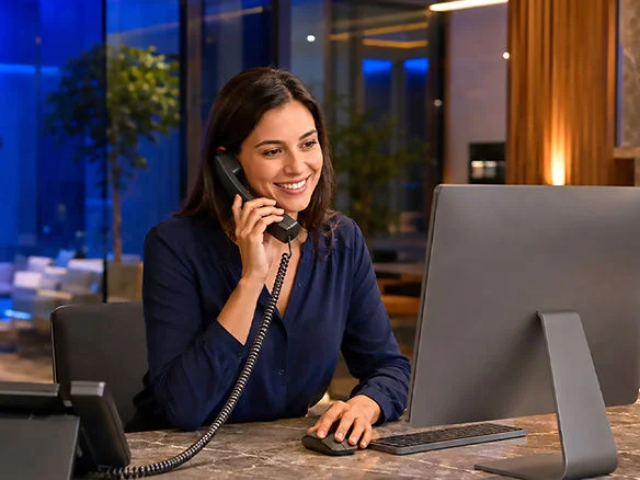 Employee taking a customer call using an Optimum Business phone system headset and desktop 