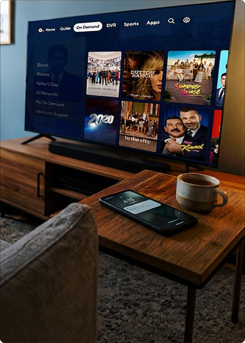 Un televisor de pantalla plana muestra el menú de streaming de Optimum en una consola; imagen de una tarjeta azul Visa de $200 junto a una taza y un teléfono
