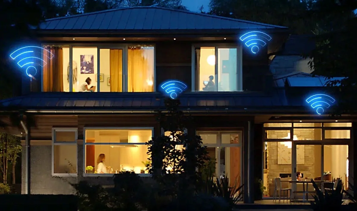 Modern two-story home at dusk with lit windows and blue WiFi signal icons over multiple rooms