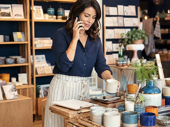 Retail employee checking store inventory on a smartphone with an Optimum Mobile for Business plan 