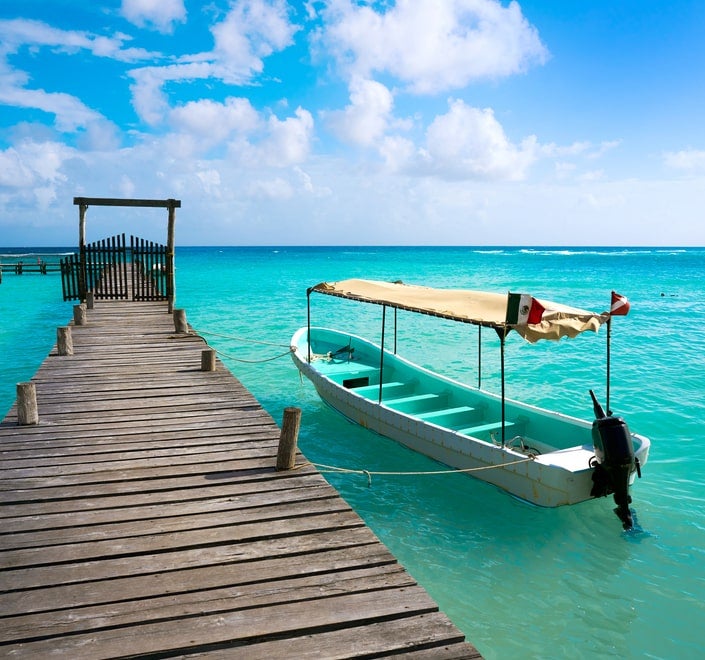 Tarjeta de un canal de televisión con imágenes de un muelle y una embarcación en las aguas turquesas del Caribe. Ideal para contenidos relacionados con viajes o retransmisiones.