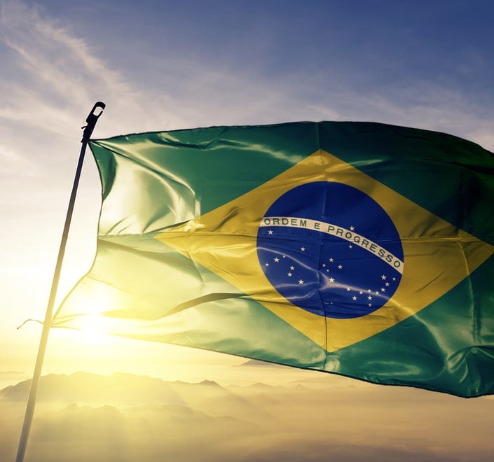 Una imagen de la tarjeta de un canal de televisión brasileño en la que se muestra la bandera de Brasil sobre un bonito cielo al atardecer.