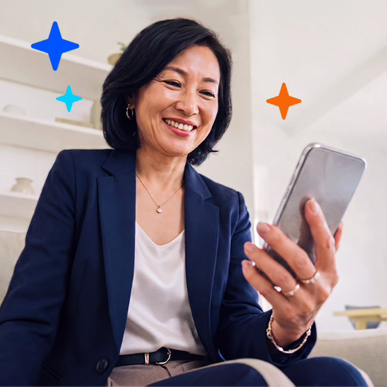 Woman in a business suit smiling while looking at her phone.