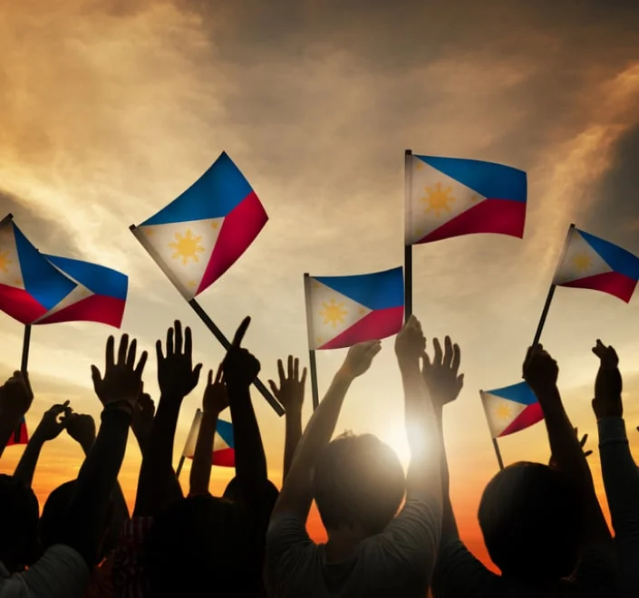 Personas con banderas de Filipinas al atardecer