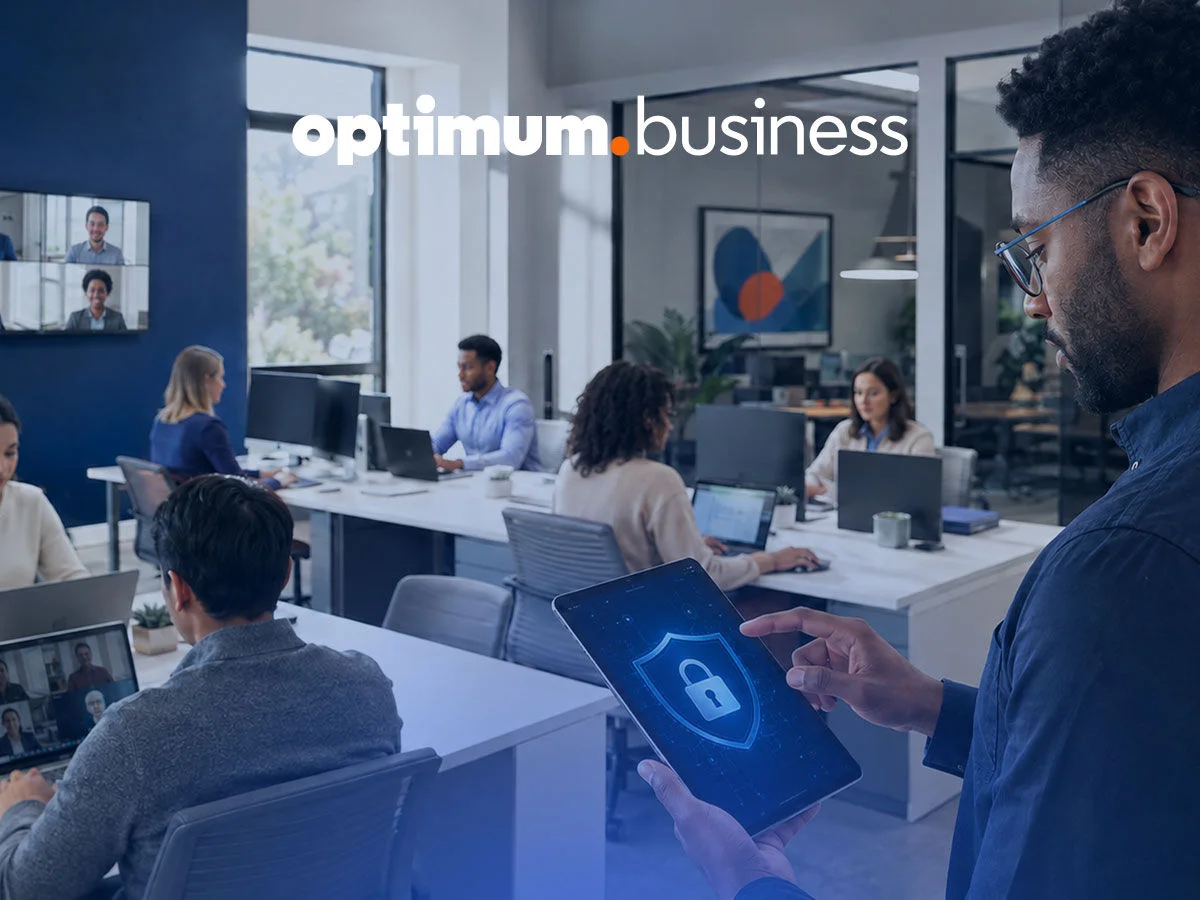Office employee holds a tablet showing a security lock icon, representing Optimum Business network security protecting the workplace.