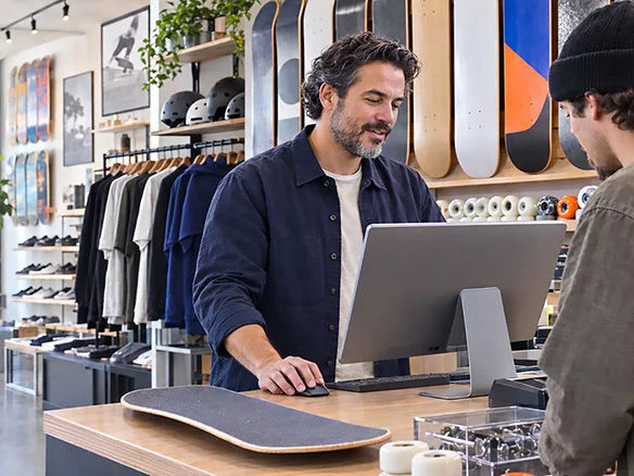 Man at a checkout counter using a tablet point-of-sale system in a retail clothing store 