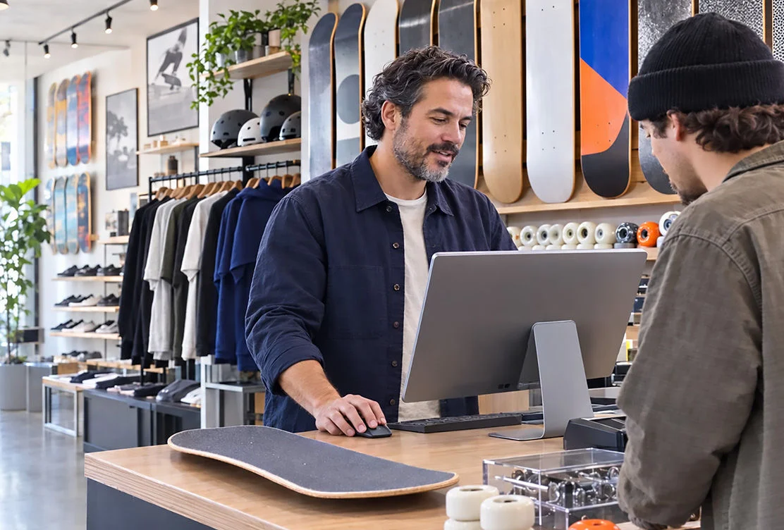 Man at a checkout counter using a tablet point-of-sale system in a retail clothing store 