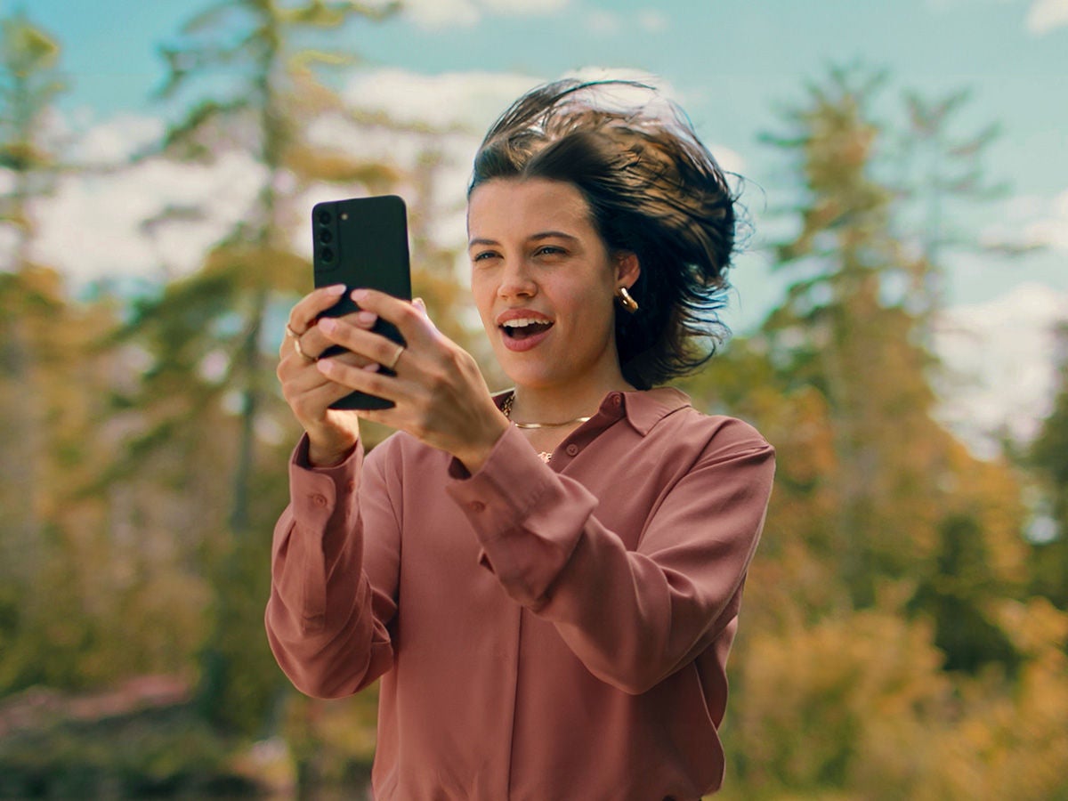 Woman Using a Mobile Phone on Optimum's 5G Network, unlocking Maximum Value