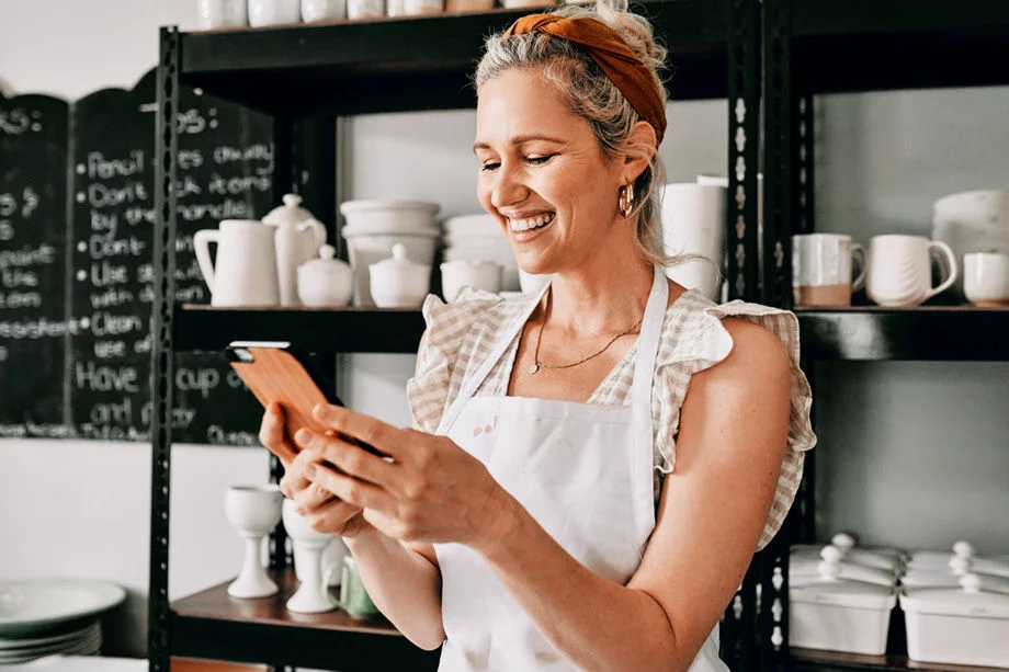 Woman smiling at phone in a kitchen.