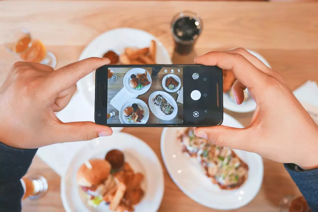 Person taking picture of three plates of food at a restaurant