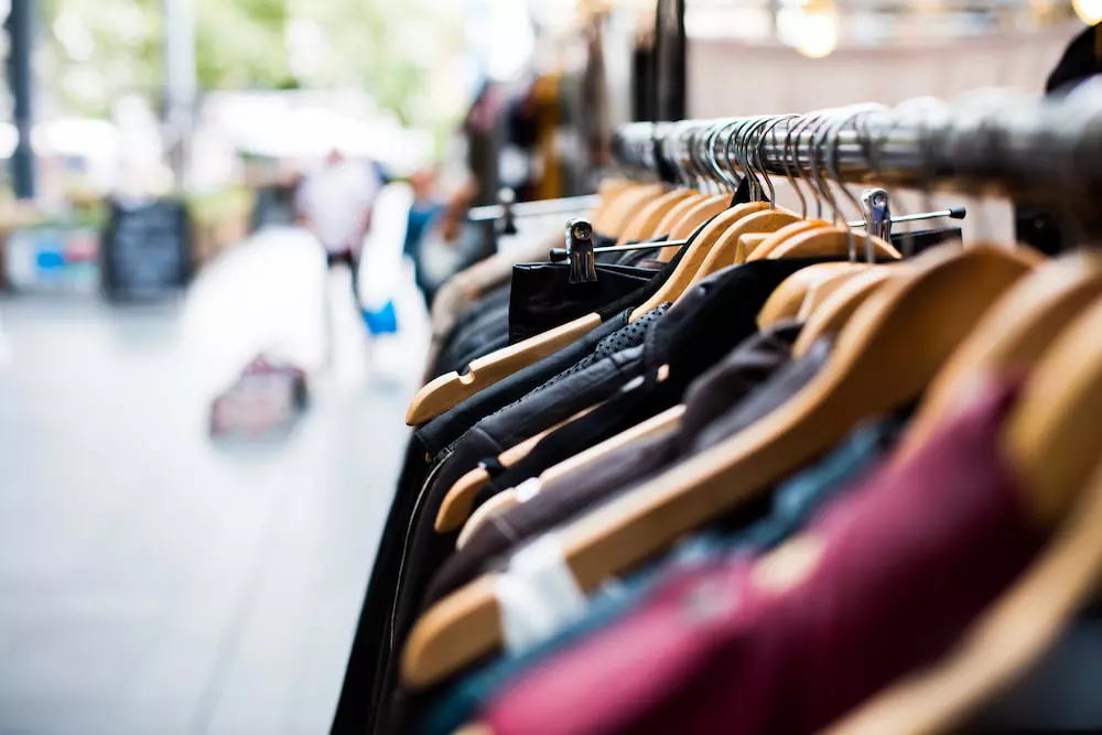 a rack of clothes outside of a store in a city