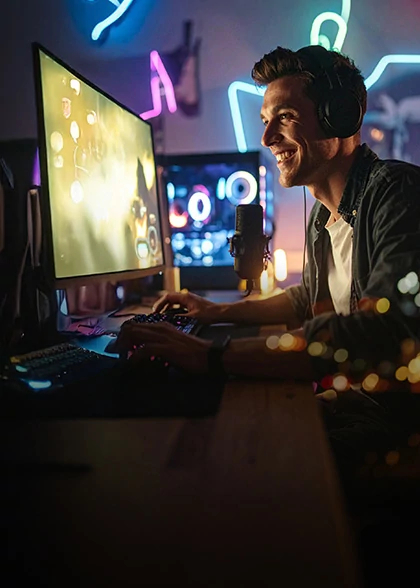 Man in headphones smiles at a glowing monitor in a gaming room lit by neon music-note signs