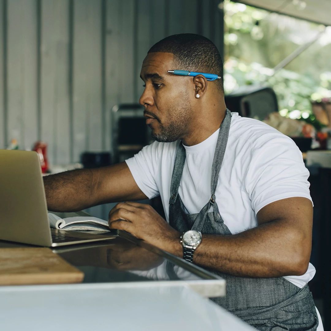 Small business owner in a cafe using a laptop, demonstrating secure brand protection and connectivity.