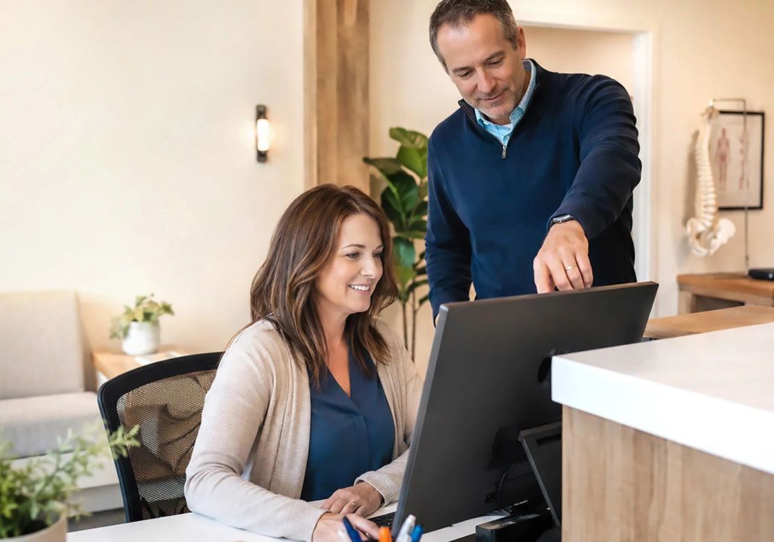 Man and woman looking together at a desktop computer monitor in a bright office