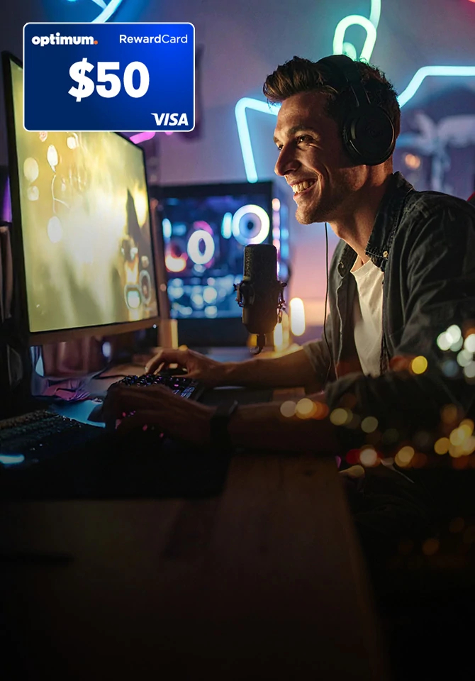 Man in headphones smiles at a glowing monitor in a gaming room lit by neon music-note signs