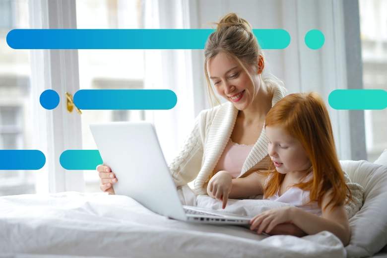 mother and daughter sitting in bed looking for something to watch on a laptop together